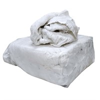 En bal med genomskinlig plast. I balen är det vita frottedukar. Ligger dukar löst ovanpå balen